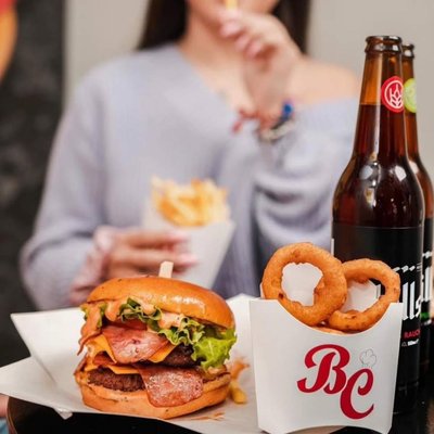 A bacon burger with onion rings and a beer